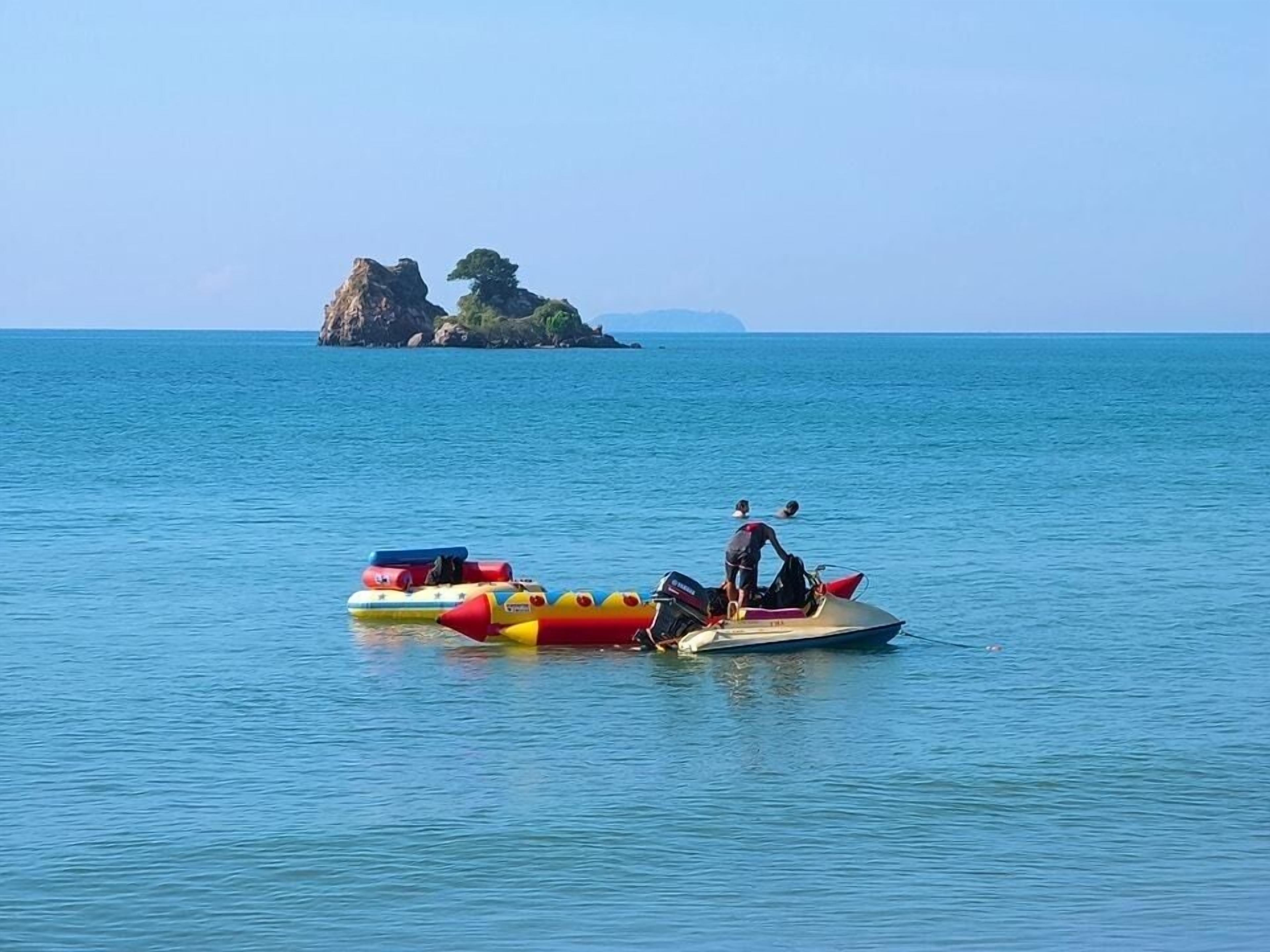Ein Wasserfahrzeug mit einer Person, das auf ruhigem Wasser treibt, mit einer kleinen Insel im Hintergrund.