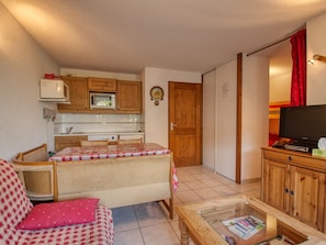 A compact living space with a kitchenette, a sofa, a coffee table, and a television.