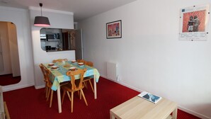 Un coin repas avec une table dressée pour quatre personnes, un banc en bois, un radiateur et une affiche accrochée au mur.
