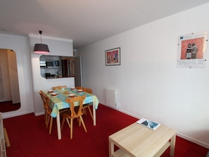 Un coin repas avec une table dressée pour quatre personnes, un banc en bois, un radiateur et une affiche accrochée au mur.