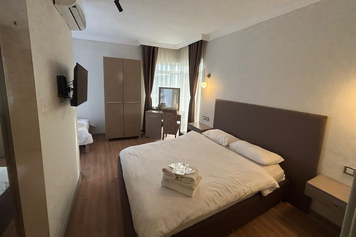 Une chambre d’hôtel avec un grand lit, un bureau, une armoire et un téléviseur.