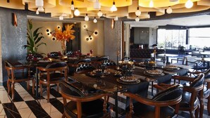 A dining area with a checkered floor, leather chairs, a central table with plates and glasses, and hanging lamps. - New Hotel Samsun (Atakum)