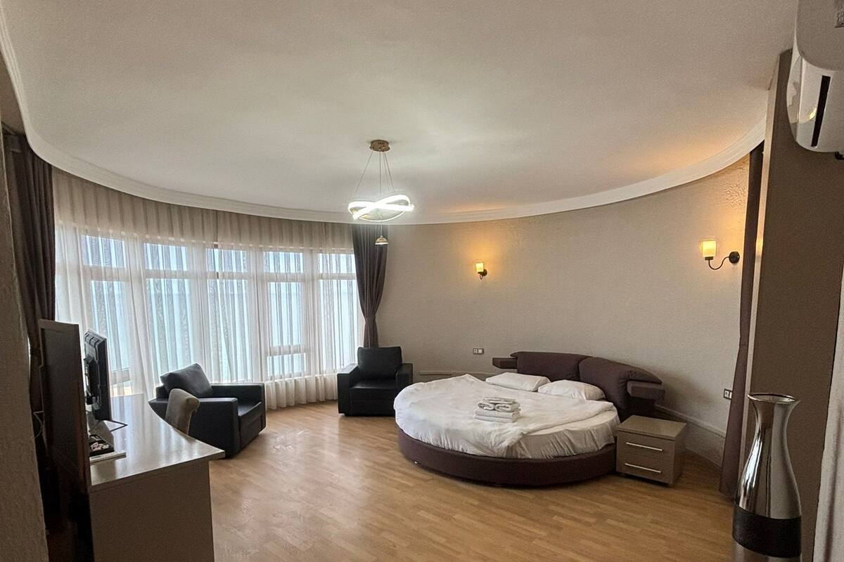 Une chambre d’hôtel moderne dotée d’un plafond incurvé, d’un lit rond, d’un bureau et d’un coin salon.