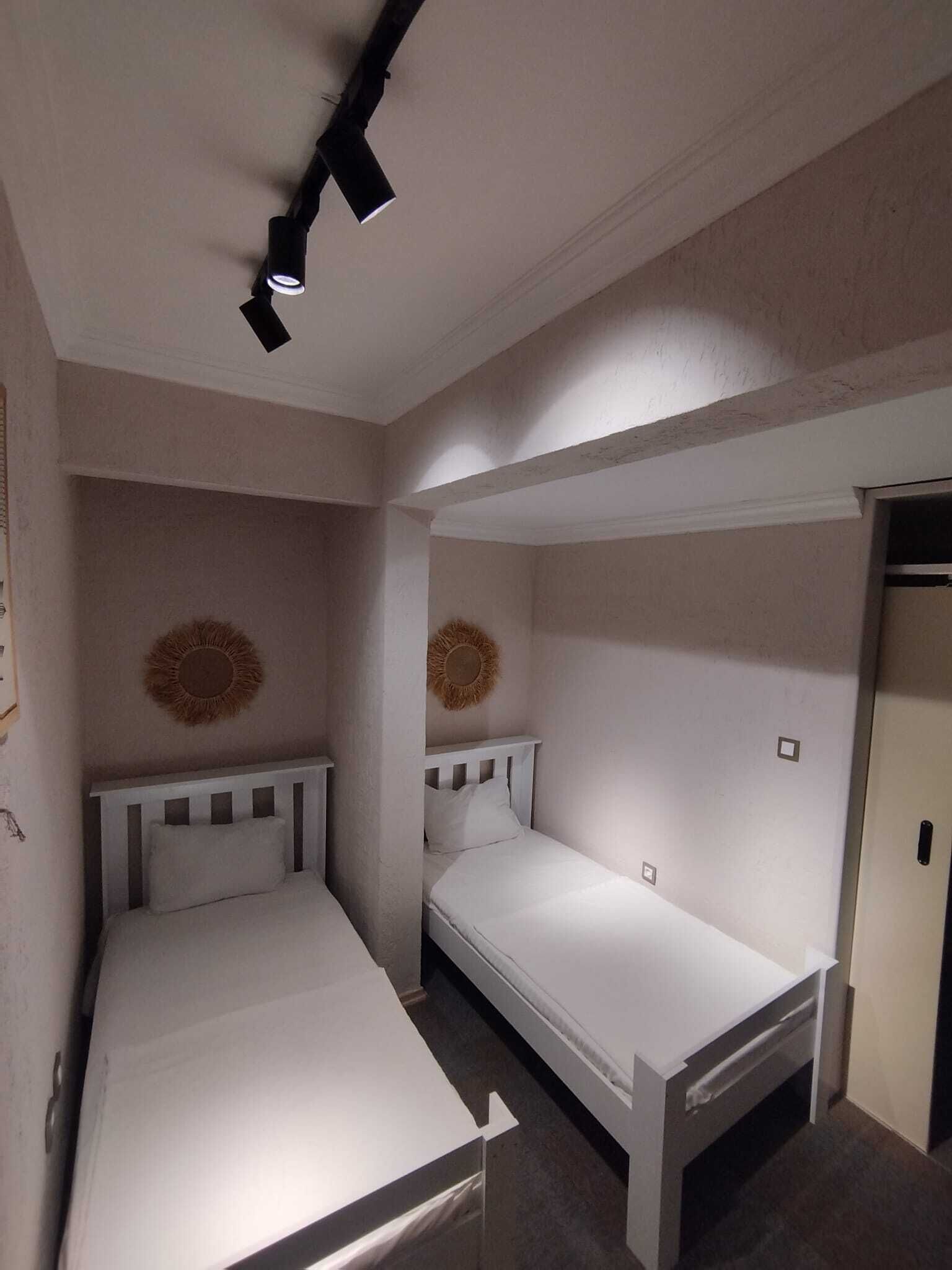 Een kleine kamer met twee eenpersoonsbedden, een tafeltje en een kledingkast.