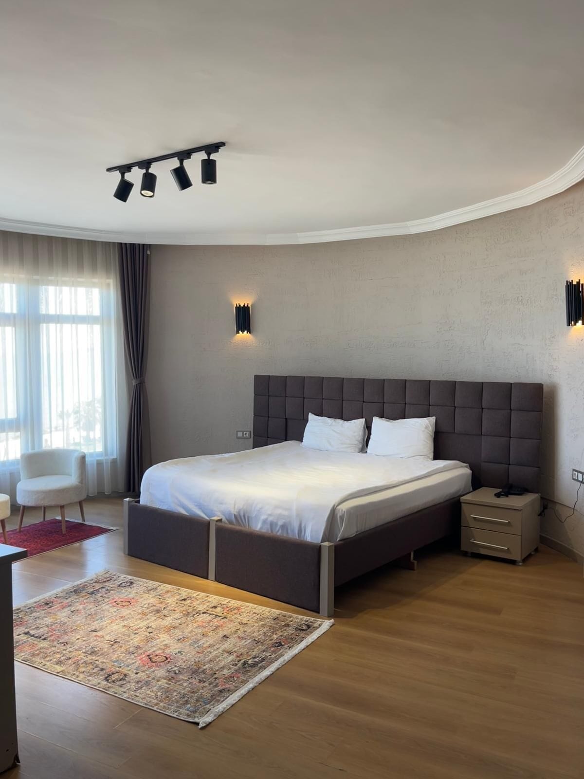Un dormitorio moderno con una cama grande, mesitas de noche, un escritorio y una silla.