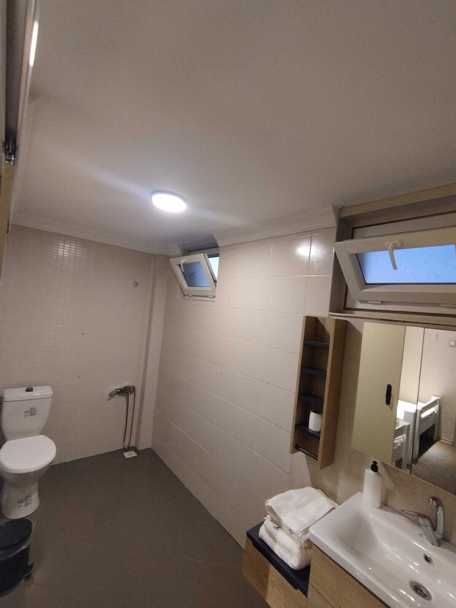 Ein Badezimmer mit Toilette, Waschbecken, Spiegel und Duschbereich.