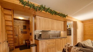 L’intérieur chaleureux d’un chalet en bois comprend un coin cuisine avec des meubles en bois et un sol carrelé.