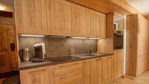 Une cuisine moderne avec des meubles en bois, une machine à café en acier inoxydable et un four encastré.