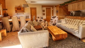 Un salon confortable avec un canapé, des fauteuils, une table basse et un coin repas comprenant une table et des chaises.