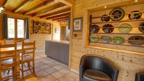 A wooden interior with a kitchen area, wooden chairs, and a wall-mounted plate display. - Chalet on the slopes with sauna and terrace, sleeps 12 (Morillon 1100)