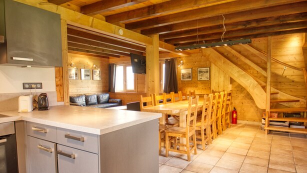 A rustic kitchen with wooden beams, a dining area with wooden chairs, and a built-in oven. - Chalet on the slopes with sauna and terrace, sleeps 12 (Morillon 1100)