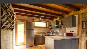 A modern kitchen with a central island, stainless steel appliances, and wooden beams. - Chalet on the slopes with sauna and terrace, sleeps 12 (Morillon 1100)