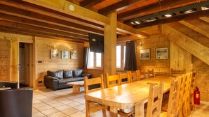 A wooden interior with a dining table, chairs, a sofa, and a fireplace. - Chalet on the slopes with sauna and terrace, sleeps 12 (Morillon 1100)