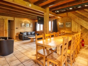 A wooden interior with a dining table, chairs, a sofa, and a fireplace. - Chalet on the slopes with sauna and terrace, sleeps 12 (Morillon 1100)