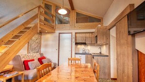 A cozy, wooden interior with a dining table, sofa, and kitchen area. - Cozy mezzanine apartment in Morillon 1100 (Morillon 1100)