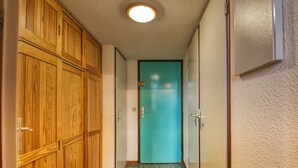 A hallway with wooden cabinets, a teal door, and patterned floor tiles. - Cozy mezzanine apartment in Morillon 1100 (Morillon 1100)