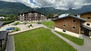 A multi-story building with balconies, a parking lot, and a grassy area. - Charming Duplex Mezzanine in Morillon Village (Morillon Village)