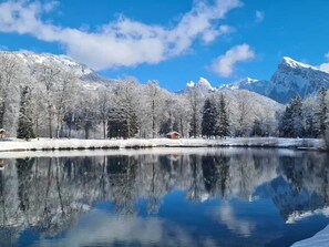 A serene winter landscape with a clear lake reflecting snow-covered trees and mountains. - Family-friendly townhouse with 2 apartments - ideal for large families (Morillon Village)