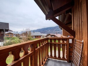 Un balcón de madera con vista a casas y montañas.