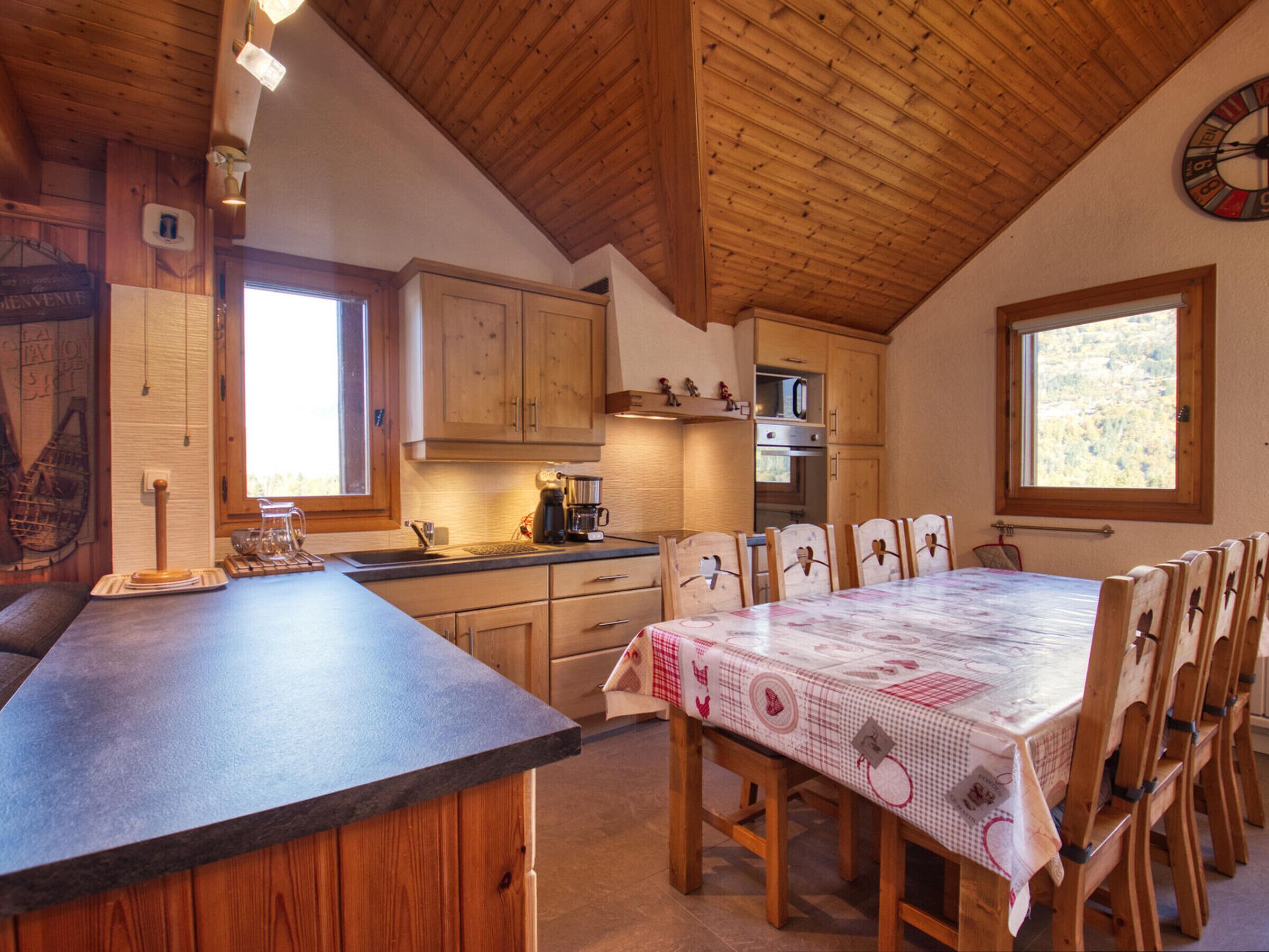 Una cocina con armarios de madera, una mesa de comedor con sillas y un reloj en la pared.