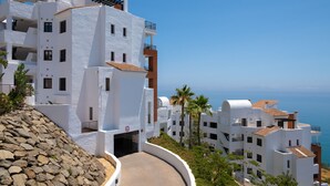 A coastal building with white walls, balconies, and a view of the sea. - 1 bedroom side sea view aparment (Torrox Costa)