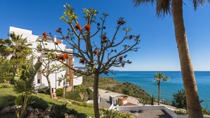 A coastal property with a view of the sea, a palm tree, and a building with a white facade. - 1 bedroom side sea view aparment (Torrox Costa)