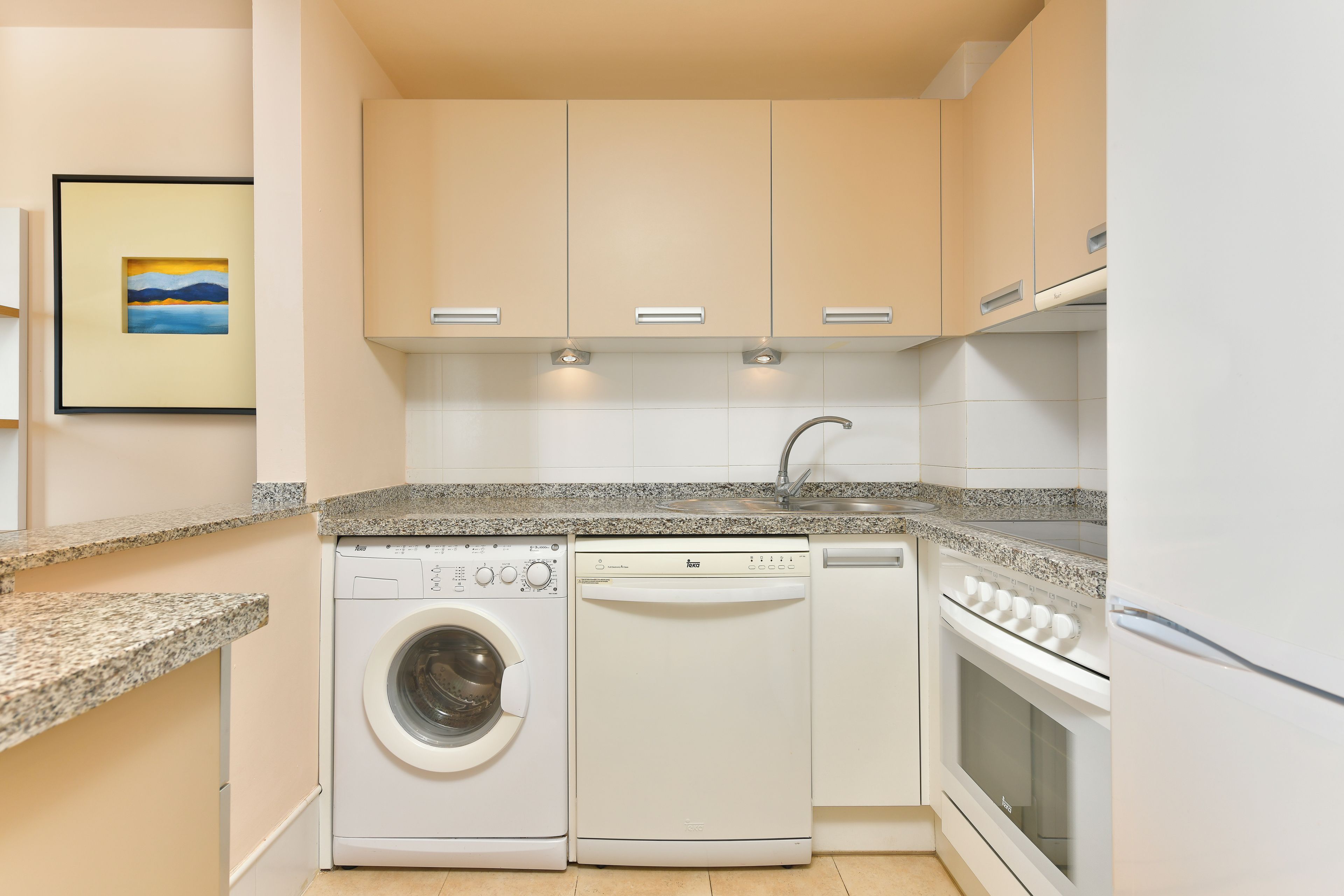 A compact kitchen with a washing machine, dishwasher, and oven.