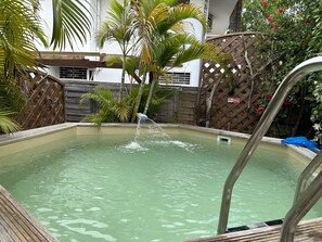 Una piscina con cubierta de madera y escalera de metal.
