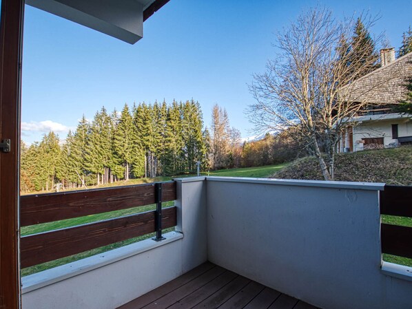 Enjoy the serene forest view from this balcony with a view of the surrounding landscape and a building in the distance.