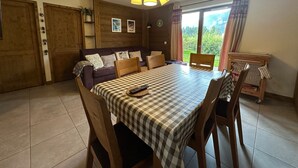 Una habitación acogedora con una mesa a cuadros, sillas de madera, un sofá y una lámpara en el techo.