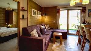 Una habitación acogedora con pared de madera, un sofá, una cama y un comedor.