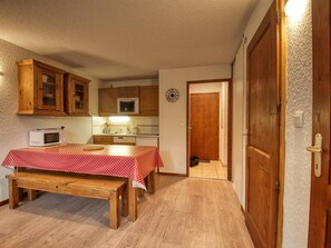 A compact kitchen with wooden cabinets, a microwave, and a dining table with a polka dot tablecloth.