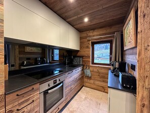 Eine moderne Küche mit Holzelementen, einem eingebauten Backofen und einem Fenster mit Blick auf eine verschneite Landschaft.