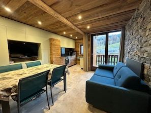 Eine moderne Küche mit Holzausstattung, einem integrierten Fernseher und einem Essbereich mit Tisch und Stühlen.