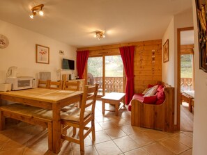 Cozy room with a dining area, kitchenette, and seating area, featuring a large window and a television.