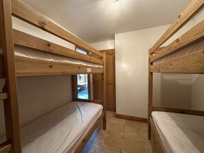 A compact room with bunk beds, wooden walls, and a tiled floor.