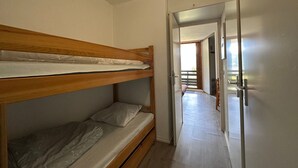 A bunk bed room with a wooden headboard, a door leading to a balcony, and a hallway with a wooden floor. - Ski-in apartment for 5 people, balcony, Morillon 1100 (Morillon 1100)