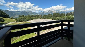 A balcony with a view of a parking area, mountains, and a sign indicating a location. - Ski-in apartment for 5 people, balcony, Morillon 1100 (Morillon 1100)