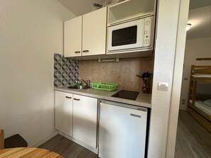 A compact kitchenette with a microwave, sink, and a small refrigerator.