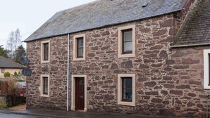 A stone building with a traditional design, featuring a central entrance and multiple windows. - Ground Floor Apartment W/large Enclosed Garden (Crieff)