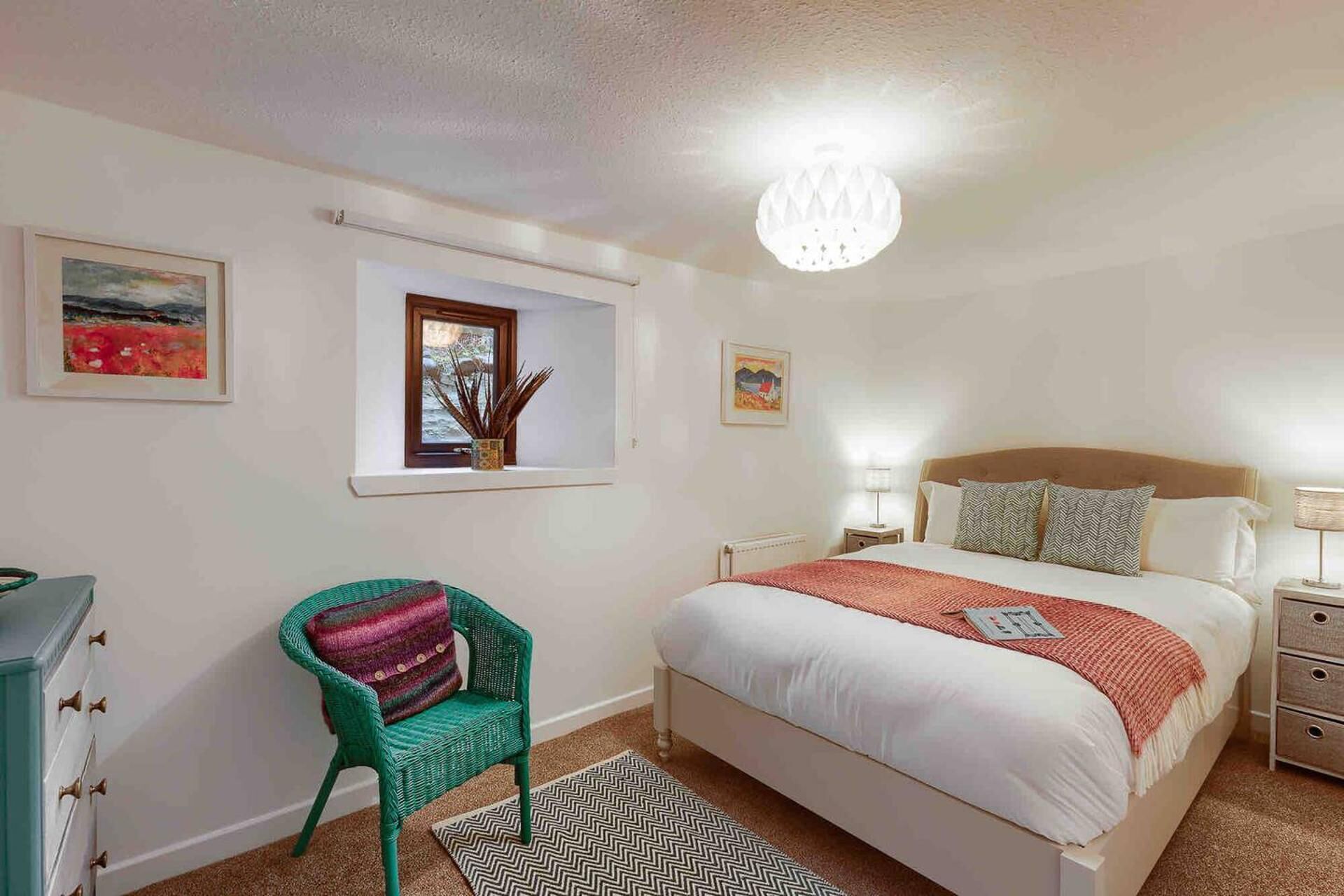 A bedroom with a bed, nightstands, a chair, and artwork on the walls.