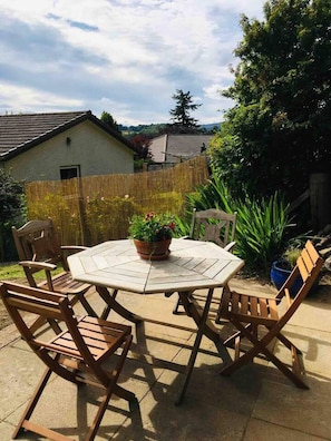 A round wooden table with six chairs, surrounded by a bamboo fence, in a backyard setting. - Ground Floor Apartment W/large Enclosed Garden (Crieff)