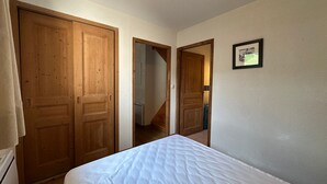 A bedroom with a bed, wooden wardrobe, and a framed picture on the wall. - Spacious 3-bedroom duplex at the slopes, parking included (Morillon 1100)