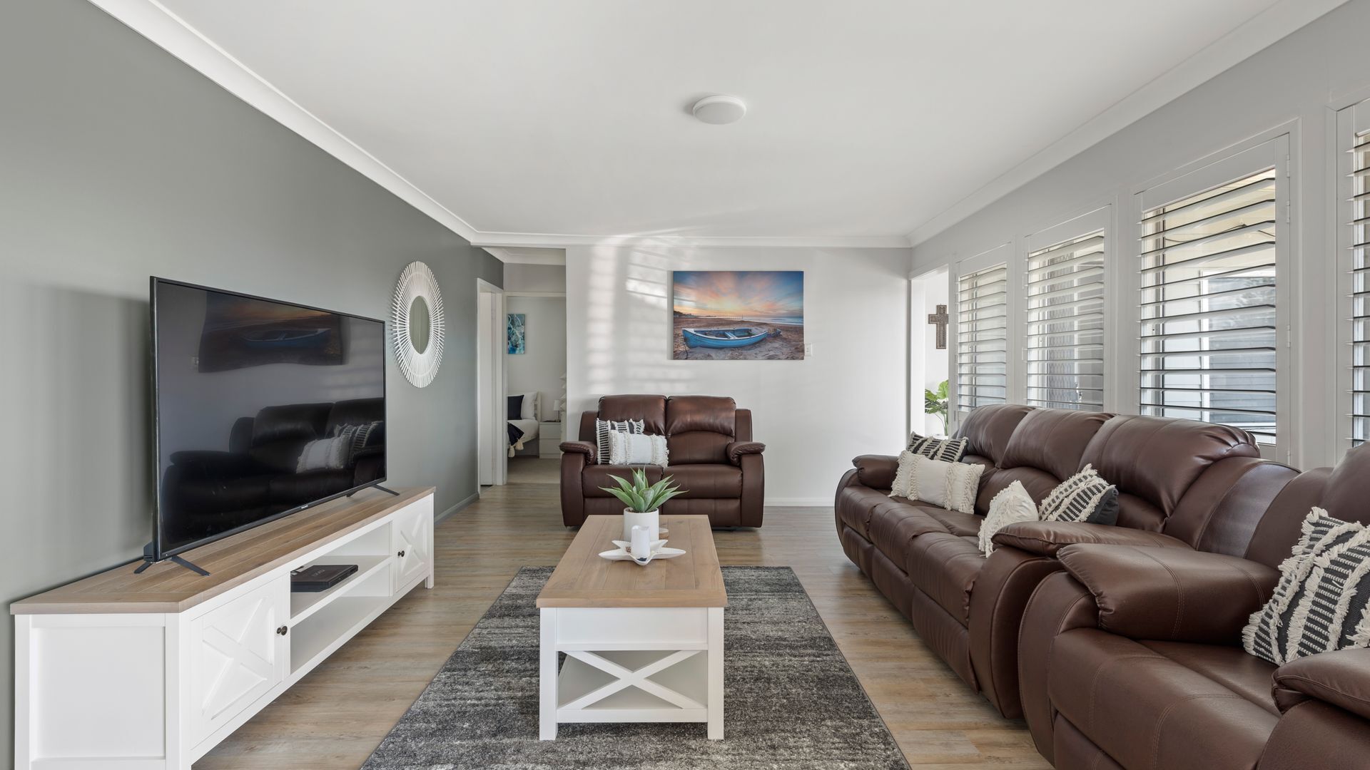 Ein modernes Wohnzimmer mit Flachbildfernseher, Ledersofas, einem Couchtisch und einem Gemälde an der Wand.
