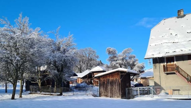 En snötäckt by med rustika trähus och en klarblå himmel.
