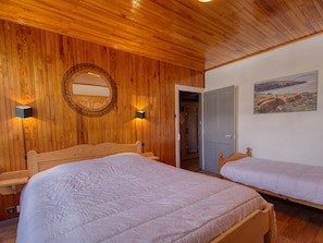 Ein Schlafzimmer mit zwei Holzbetten, einer Holzbalkendecke, einem runden Spiegel und einem Bild an der Wand.