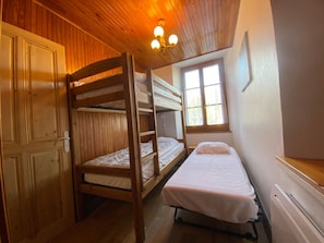 A bunk bed room with wooden walls and a window.