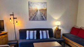 Ett mysigt vardagsrum med en mörkblå soffa, ett träbord och en tv som står på ett träställ.