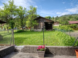 A rural setting with a wooden barn, a fenced area, and a concrete barrier with a potted plant.