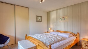 A bedroom with a wooden bed, a bedside table, a chair, and a small cabinet. - Renovated apartment near lake and shuttle, 4 pers, non-smoking, no internet (Morillon Village)